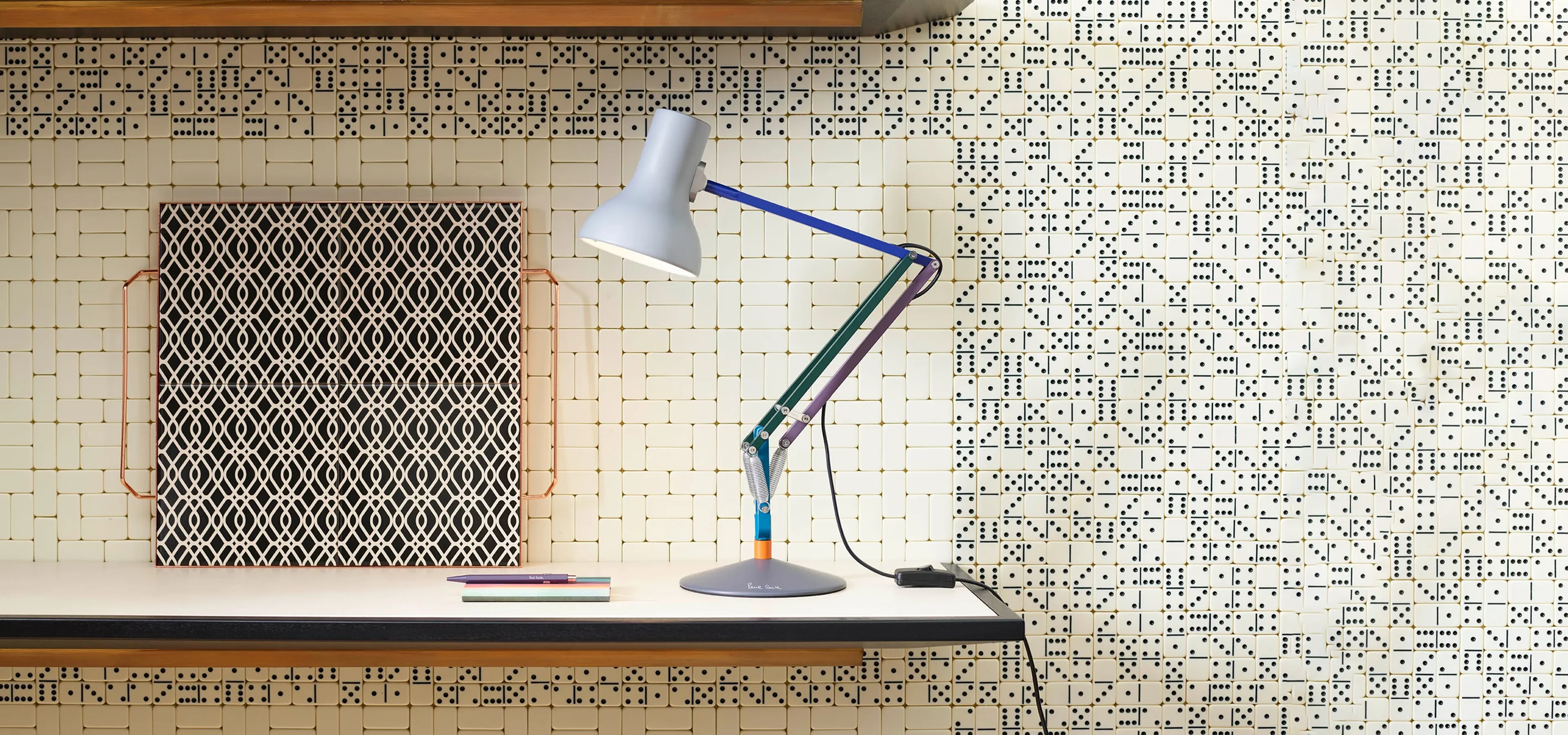 Anglepoise lamp on a patterned desk and wall