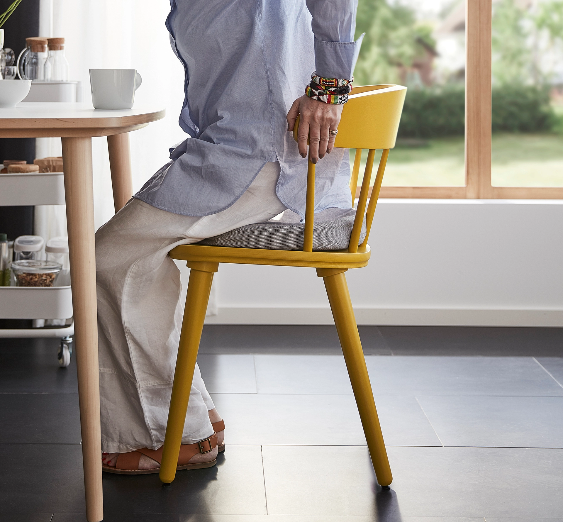 Elderly lady getting up from a yellow wooden chair