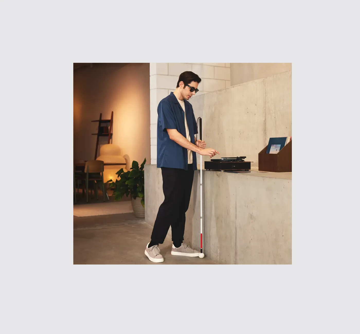 WeWalk Chain blends arifical intelligence and sensory tech to help sight impaired navigate the world. A sight impaired male is using a record player in a hotel lobby.